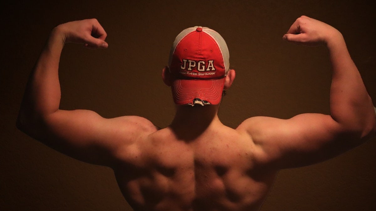 A man flexing his muscles in front of a brown background